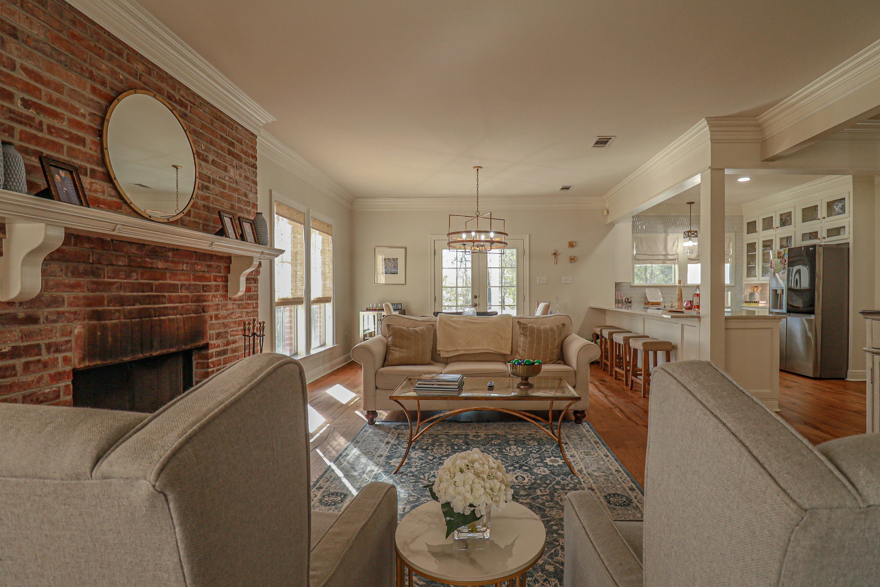 Living room with a brick fireplace, crown molding, painted trim, and built-in cabinetry